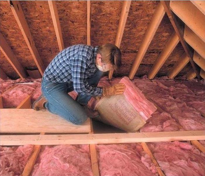 Man checking insulation in an attic 